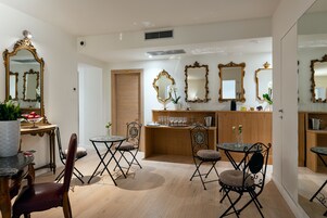 A dining area with a marble table, cushioned chairs, and a wooden counter with glassware.