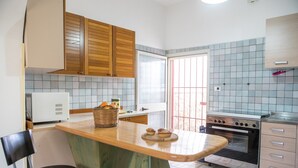 A compact kitchen with wooden cabinets, a built-in oven, and a tiled backsplash.