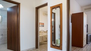 A hallway with a wooden door, a mirror, and a tiled floor.