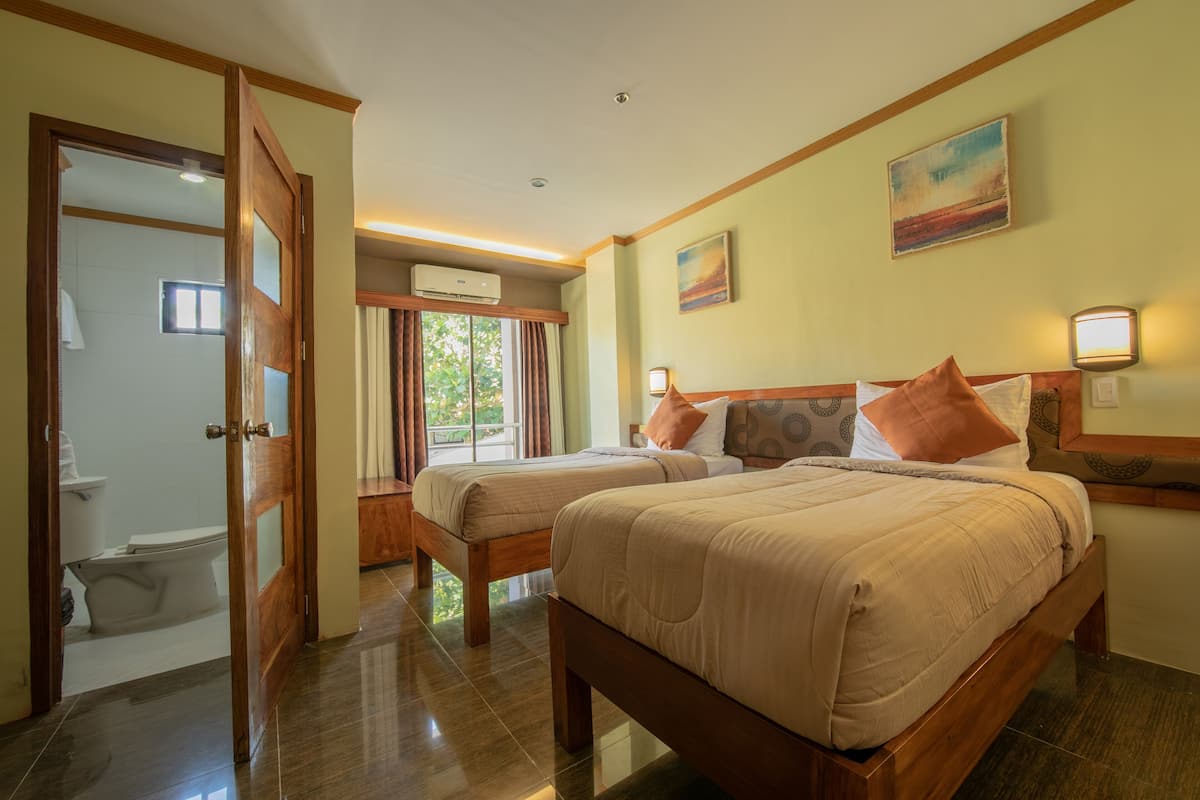 Une chambre d’hôtel avec deux lits, une salle de bain et une fenêtre avec des rideaux.