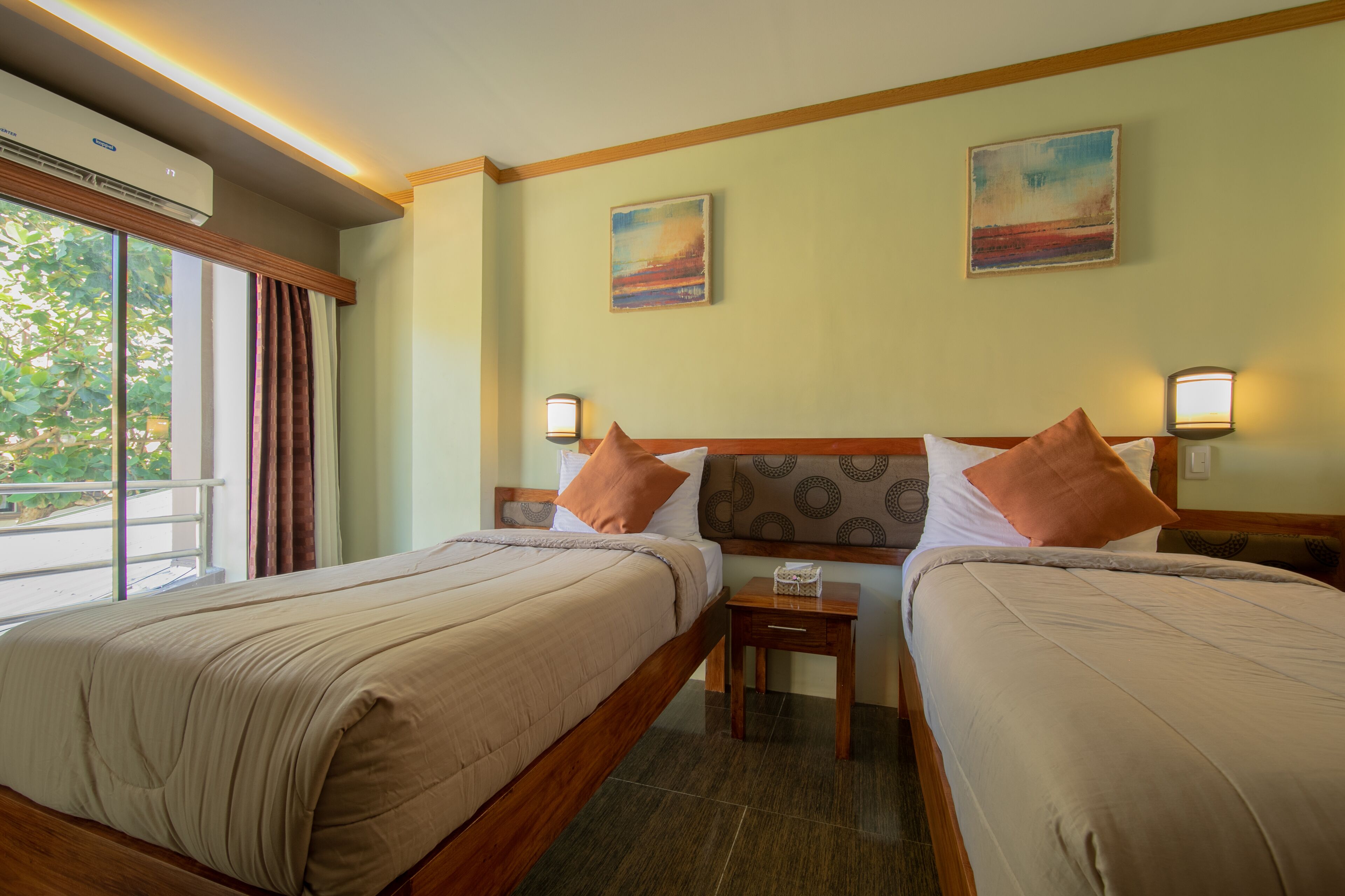 A hotel room with two beds, a nightstand, and a window with curtains.