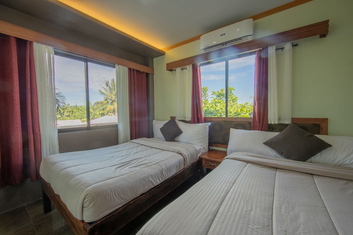Une chambre d’hôtel avec deux lits, une table de chevet et un appareil de climatisation.