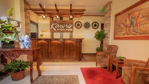 Un espace d’accueil avec un bureau en bois, un tapis rouge et un tableau accroché au mur.