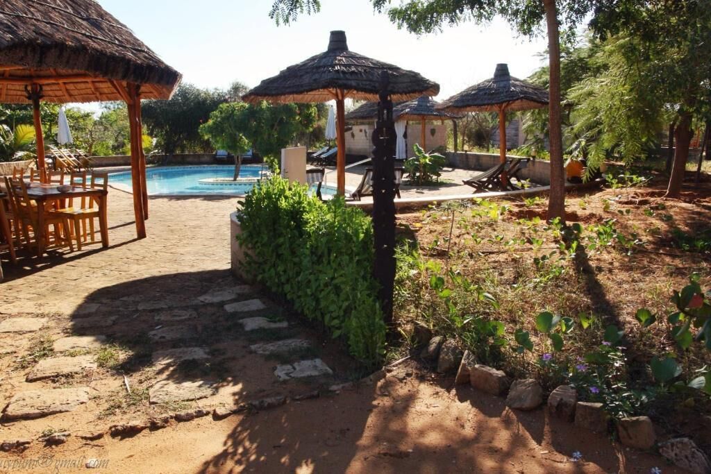 A pool area with thatched umbrellas, lounge chairs, and a stone pathway.