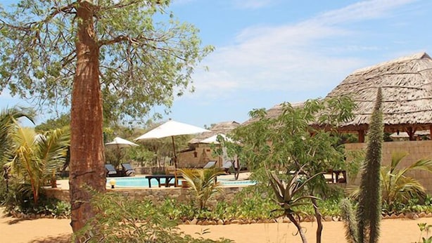 Un resort con piscina, edificios de techo de paja y palmeras.