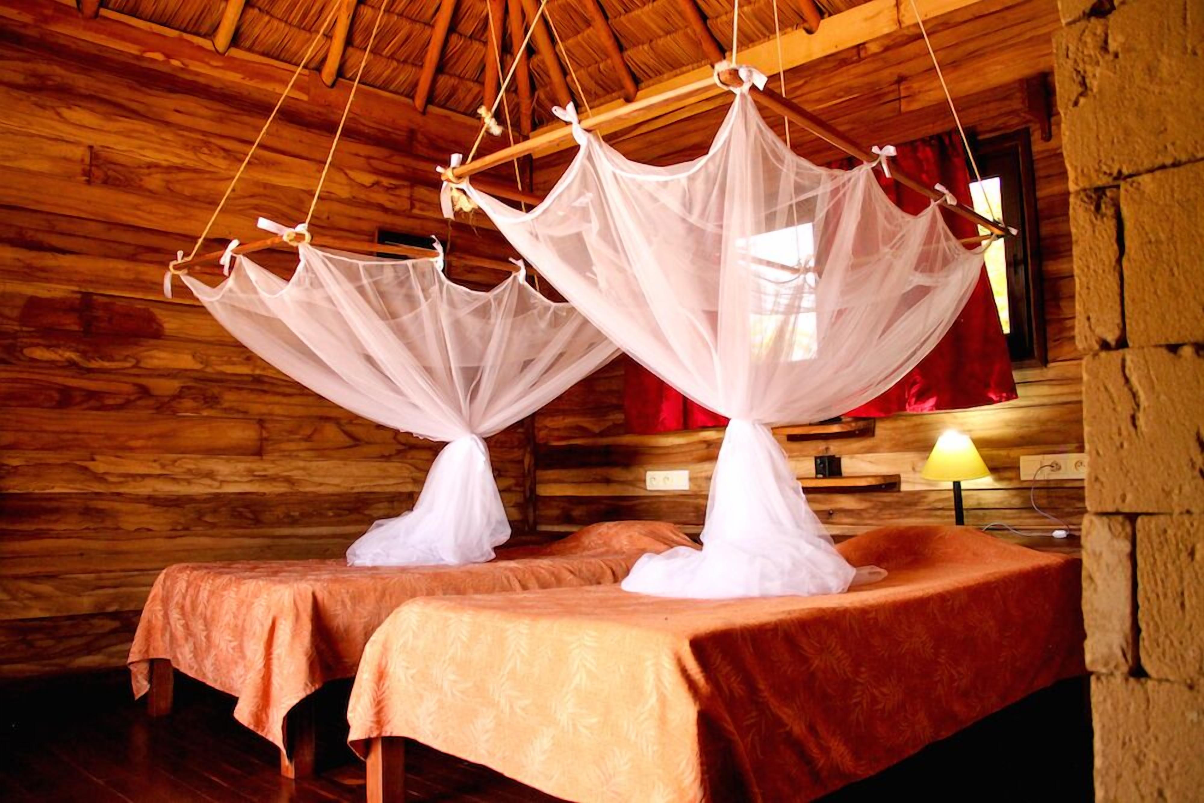 Una habitación de cabaña de madera con dos camas, cada una con dosel.