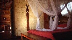 Una habitación con una cama de madera, un banco, una pared de ladrillo y una puerta de madera.