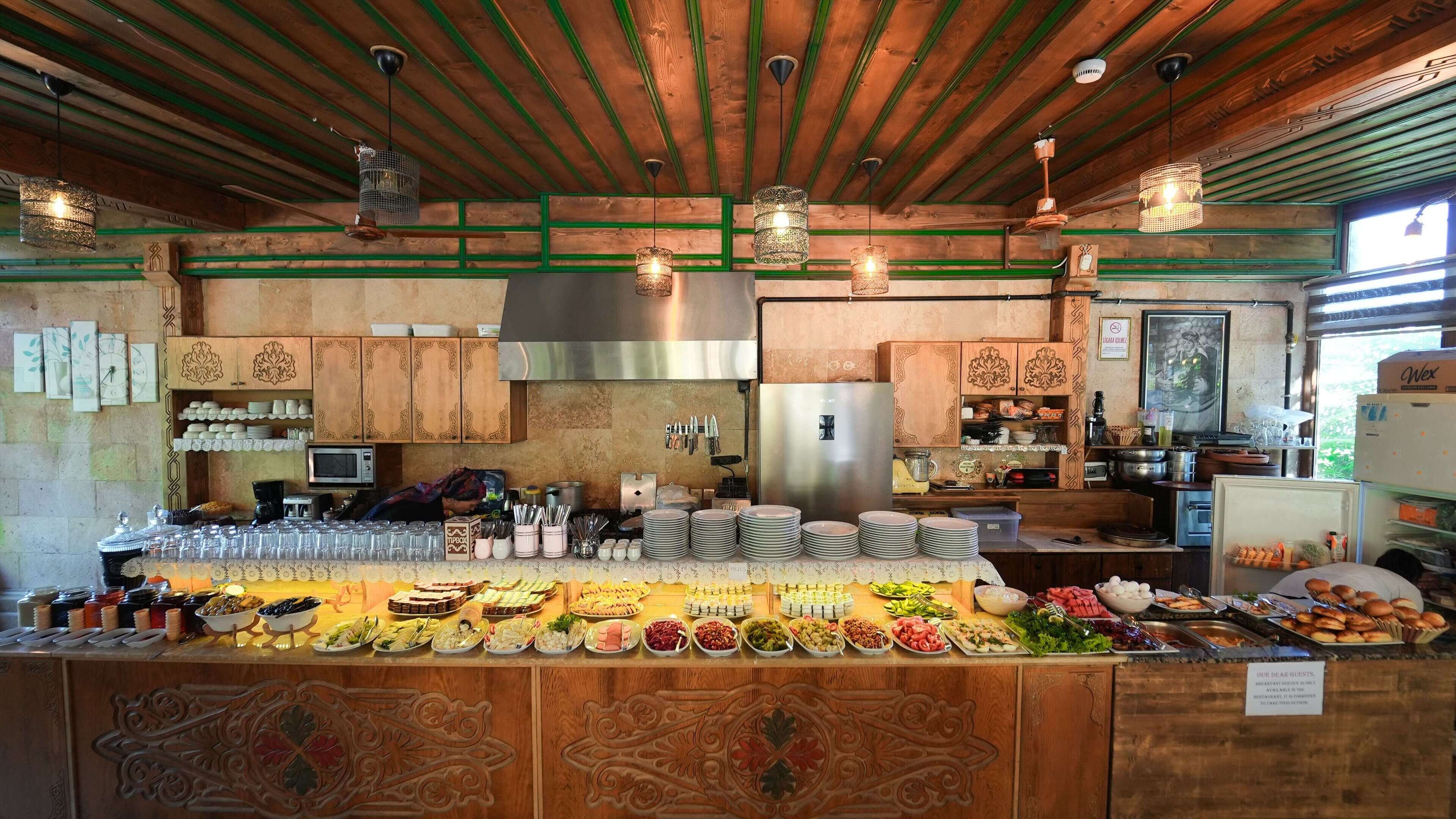 Un montaje de buffet con diferentes alimentos, utensilios, armarios de madera y una zona de cocina con electrodomésticos.