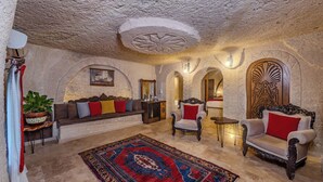 A spacious living room with a large rug, sofas, and a fireplace. - Grand Elite Cave Suites (Nevsehir)