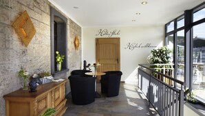 Un intérieur moderne avec un mur en pierre, une porte en bois et un balcon doté d’une balustrade.