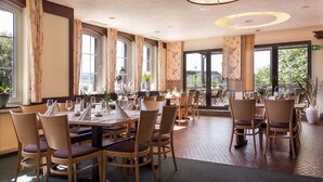 Un restaurant doté de nombreuses tables et chaises, de grandes fenêtres et offrant une vue sur l’extérieur.