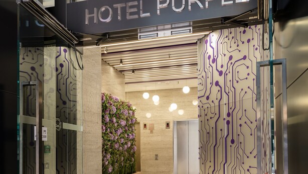 Een moderne hotelentree met een bord waarop 