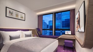 Een moderne hotelkamer met een groot bed, een bureau en uitzicht op stadsgebouwen.