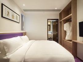 Habitación de hotel con una cama grande, un armario de madera, un baño con espejo y un cuadro enmarcado en la pared.