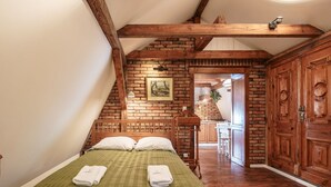 A room with a wooden bed, a brick wall, and a wooden wardrobe. - Old House Apartments Poznań (Poznan)