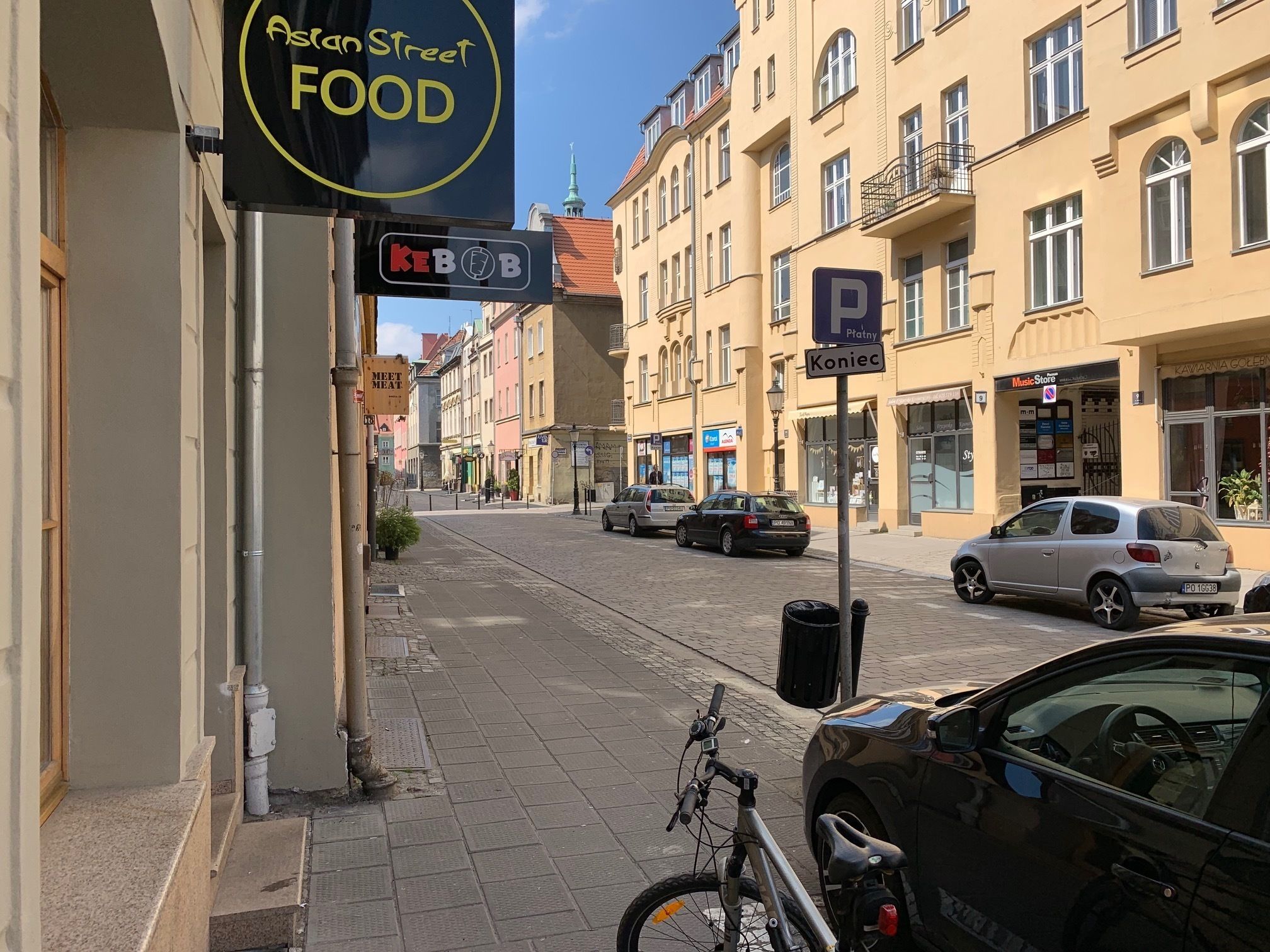 A street view with buildings, a bicycle, and parked cars.