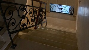 A staircase with ornate black railings, a wall-mounted mirror, and a decorative metal panel. - Old House Apartments Poznań (Poznan)