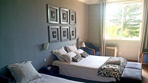 Habitación de hotel con dos camas, una ventana que ofrece vistas a la vegetación y cuadros en la pared.