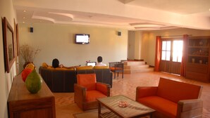 Amplia sala de estar con un conjunto de sofás, una mesa de centro y un televisor montado en la pared.