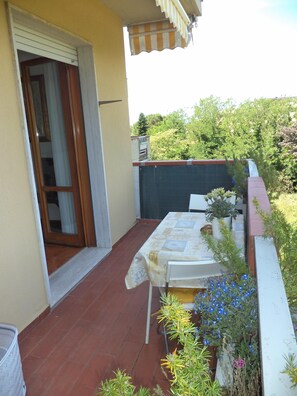 Une terrasse avec une table et des chaises, une porte coulissante et des plantes en pot.