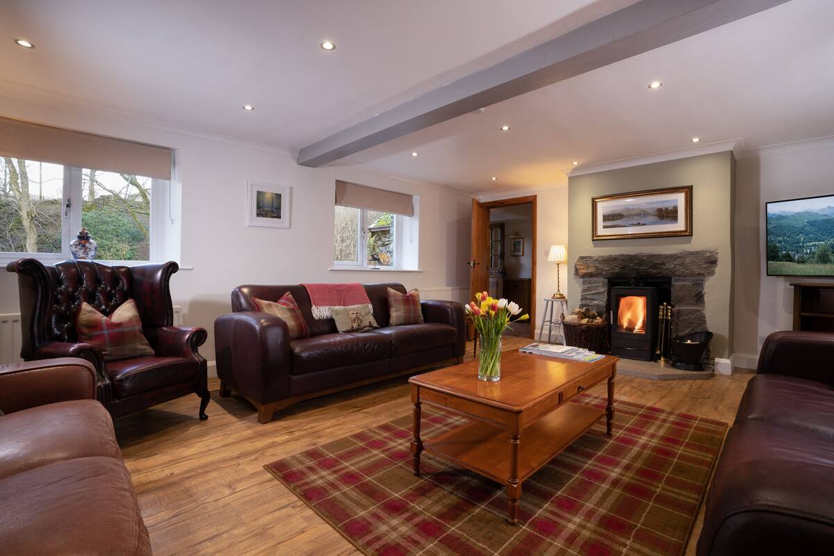 A cozy living room with leather sofas, a fireplace, and a large window.