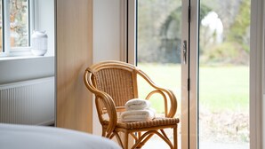 A wicker chair with towels, a window, and a view of a garden. - Low Jock Scar Country Estate (Kendal)