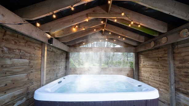 A hot tub in a wooden cabin with string lights above. - Low Jock Scar Country Estate (Kendal)