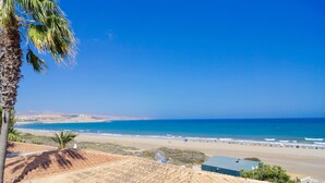 Vista costera con playa, océano y colinas lejanas.