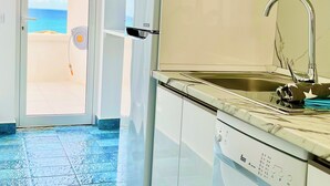 Una cocina moderna con armarios blancos, un microondas integrado y un lavamanos de acero inoxidable.