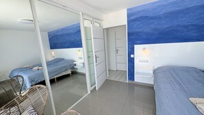 Una habitación de hotel moderna con dos camas, un separador de vidrio y vistas a la ciudad.