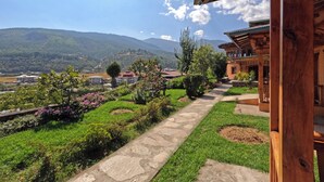 A wooden building with a stone pathway leading to a lush garden with various plants and flowers. - Rema Resort (Paro)