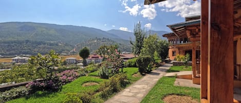 A wooden building with a stone pathway leading to a lush garden with various plants and flowers.