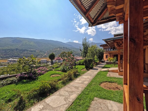 A wooden building with a stone pathway leading to a lush garden with various plants and flowers. - Rema Resort (Paro)