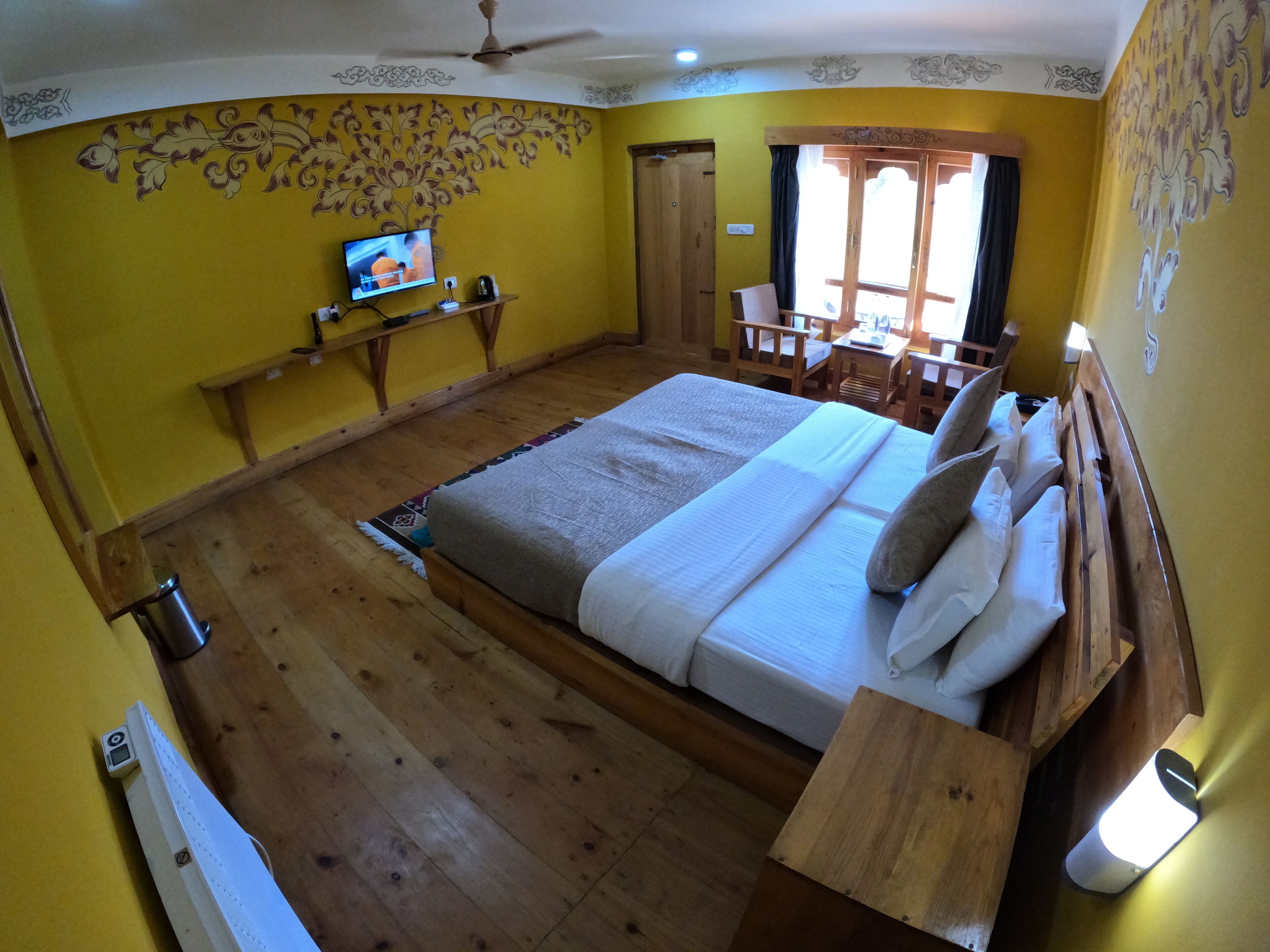 A bedroom with a bed, wooden furniture, a television, and a window with curtains.