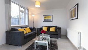 Ein modernes Wohnzimmer mit zwei grauen Sofas, einem Glastisch und einer Stehlampe.