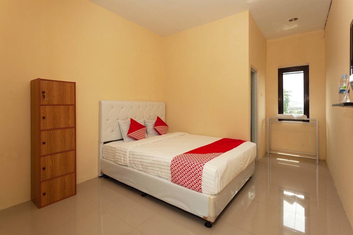 A bedroom with a bed, a wardrobe, and a window.