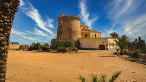 A historic building with a tower, surrounded by palm trees and a clear sky.