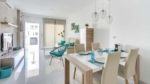 A modern dining area with a wooden table, white chairs, and hanging pendant lights.