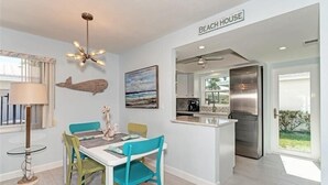 A modern kitchen with a stainless steel refrigerator, a dining area with a table and chairs, and a ceiling fan. - Crystal Sands Villa 12 - Private Beach (Sarasota)
