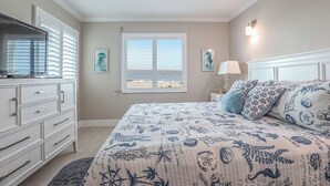 Ein Schlafzimmer mit Bett, Kommode, Fenster und Deckenventilator.