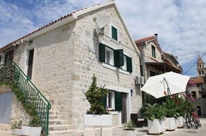 A stone building with a staircase, potted plants, and a bicycle. - Holiday Home Old House (Kastela)