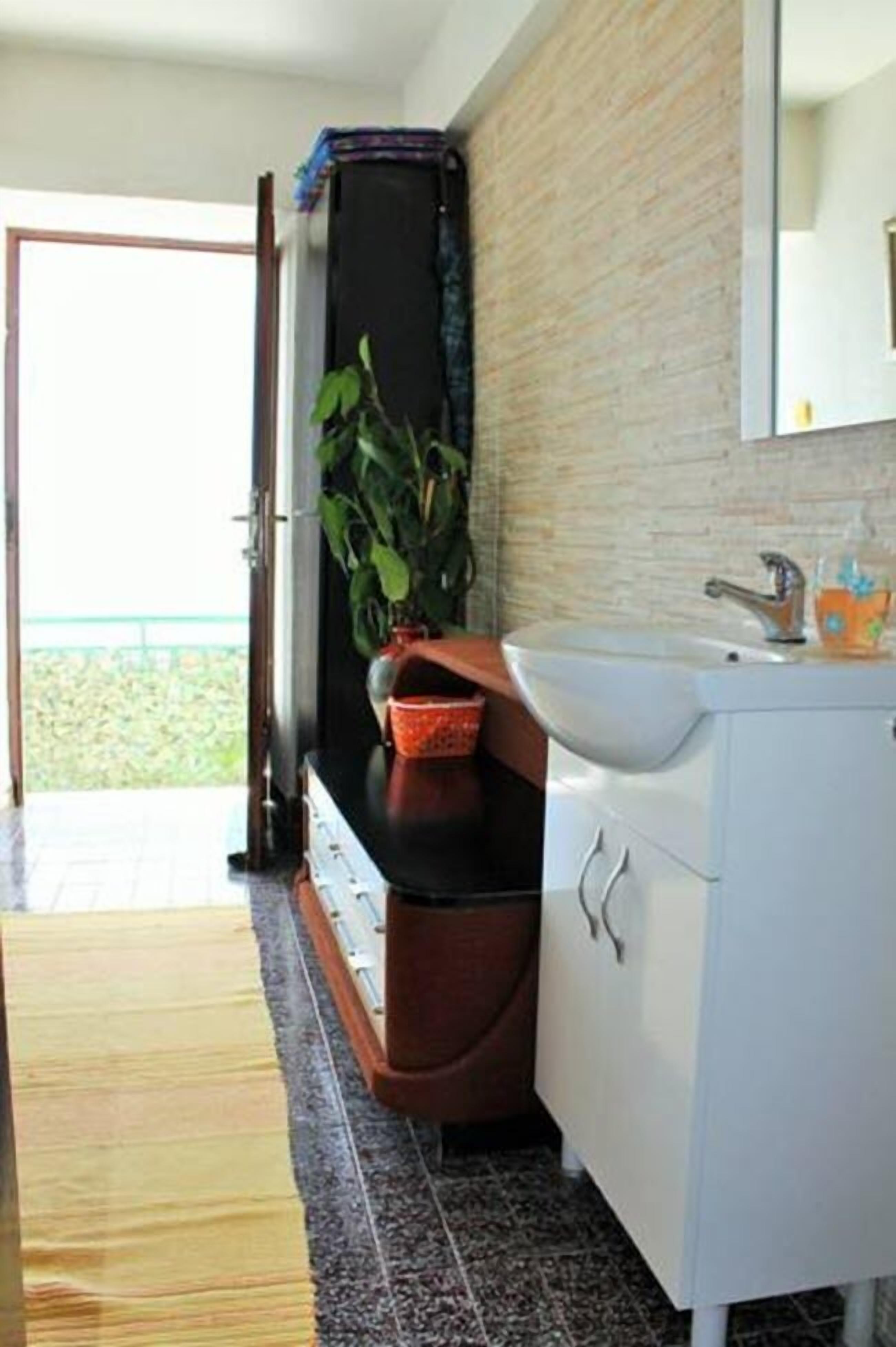 Een badkamer met een wastafel, spiegel en een plant in een pot.