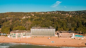 A coastal hotel with multiple buildings, a beach, and a forested hillside in the background. - Marina Sunny Day Resort (Varna)