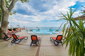 Una piscina al aire libre de temporada, sombrillas, tumbonas