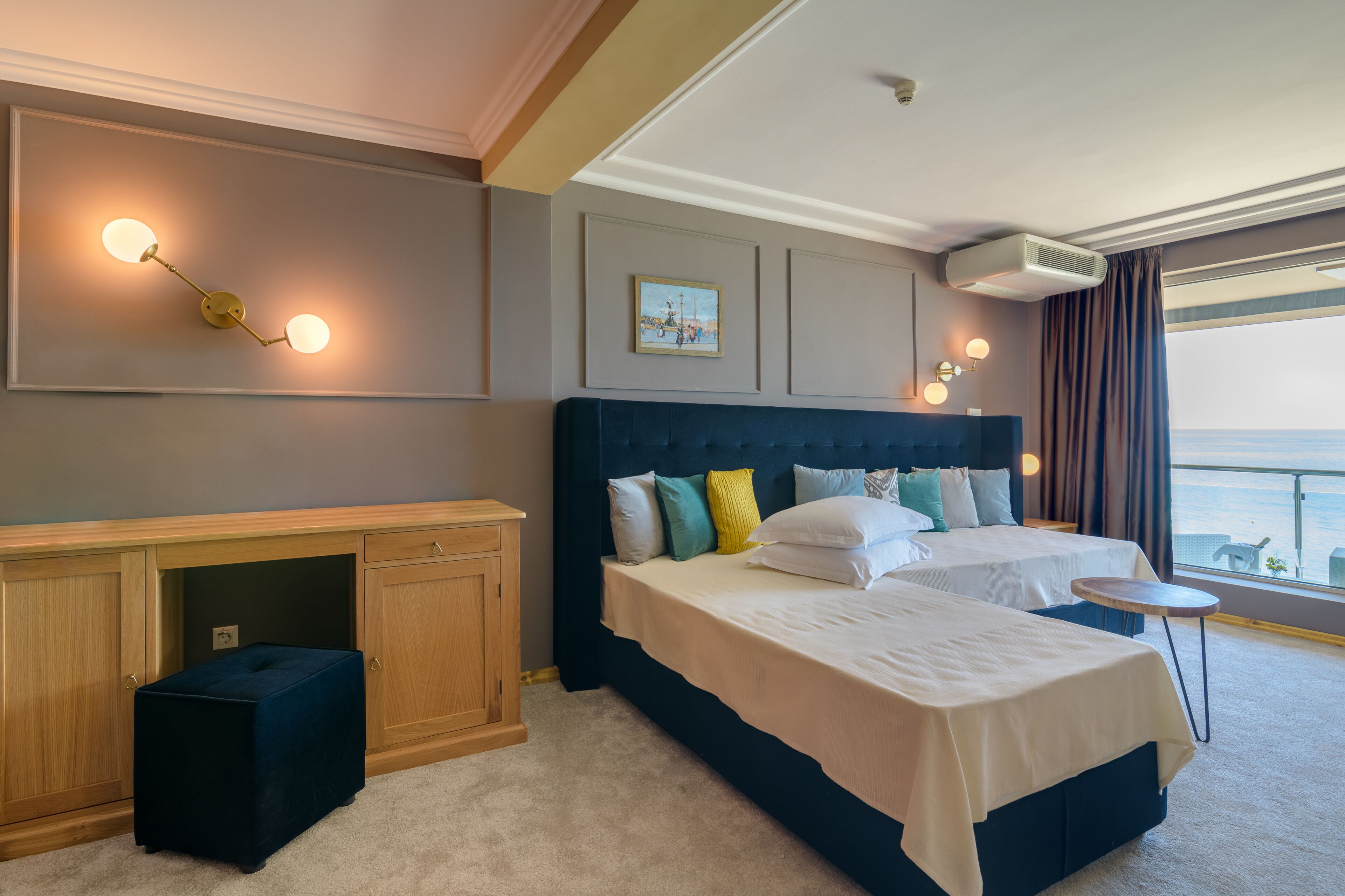 A hotel room with a large bed, a desk, and a view of the sea.