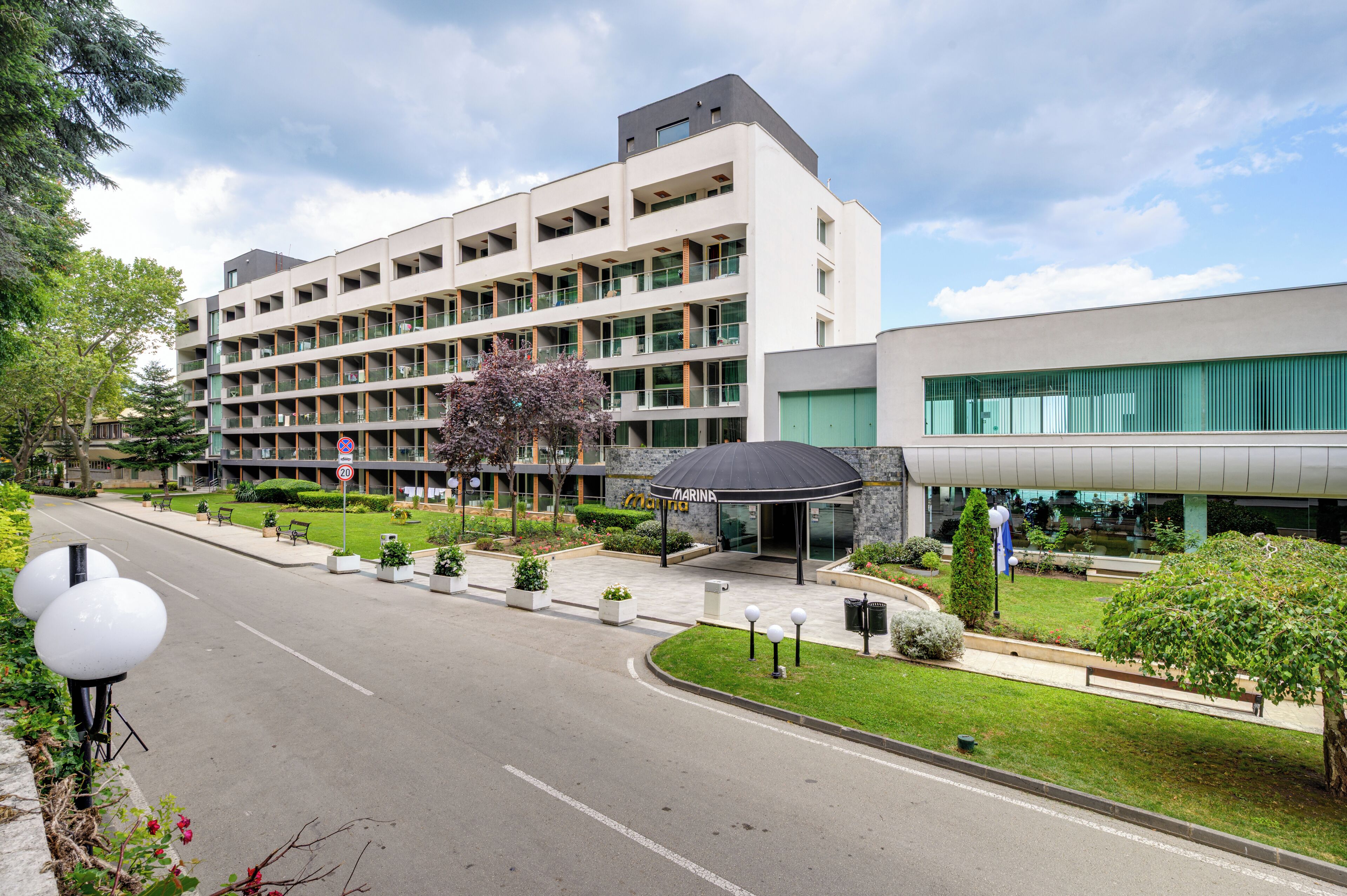 Un hôtel à plusieurs étages, doté d’un design moderne, avec une entrée couverte et une cour aménagée.