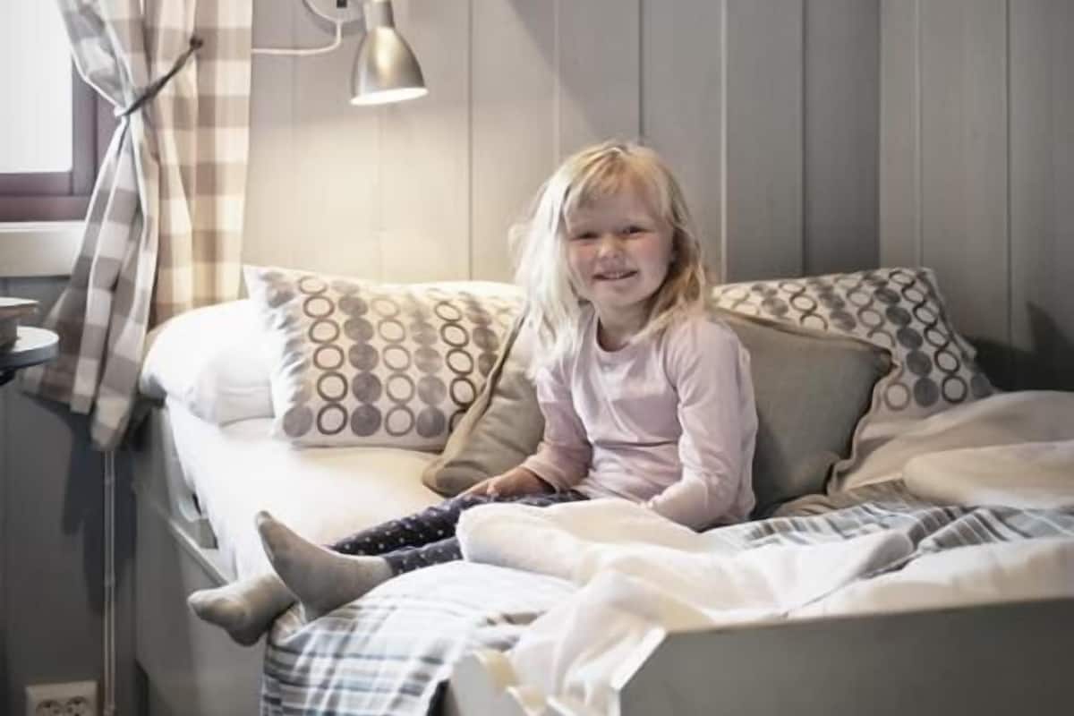 A bunk bed with a child sitting on the lower bunk and another child climbing the upper bunk.