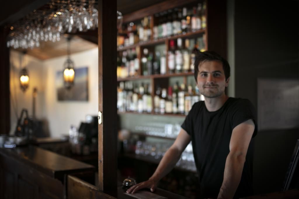 Un'area bar con un barista, scaffali pieni di bottiglie di liquore e luci a sospensione.