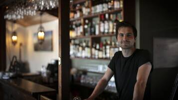 Un'area bar con un barista, scaffali pieni di bottiglie di liquore e luci a sospensione.