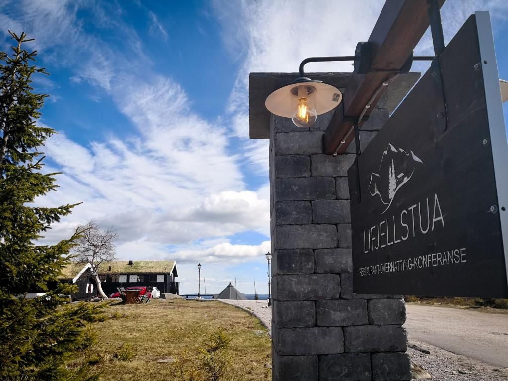 A sign for LIFELLSTUA with a clear sky and a building in the background.